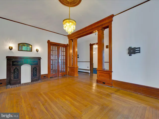 a view of an empty room with window and hardwood floor