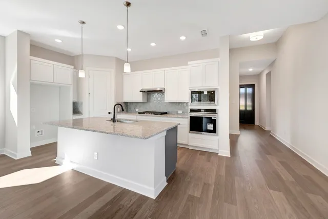 a large kitchen with granite countertop a large counter top a sink stainless steel appliances and cabinets