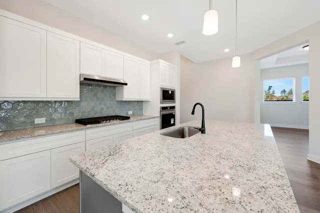 a kitchen with stainless steel appliances granite countertop a sink a stove and a wooden cabinets