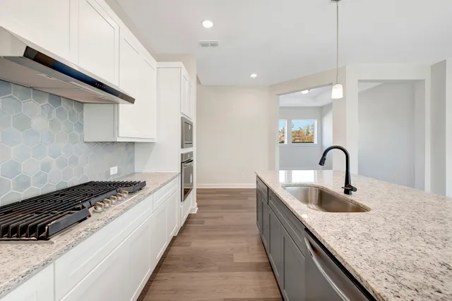 a kitchen with kitchen island granite countertop a sink a counter space and cabinets