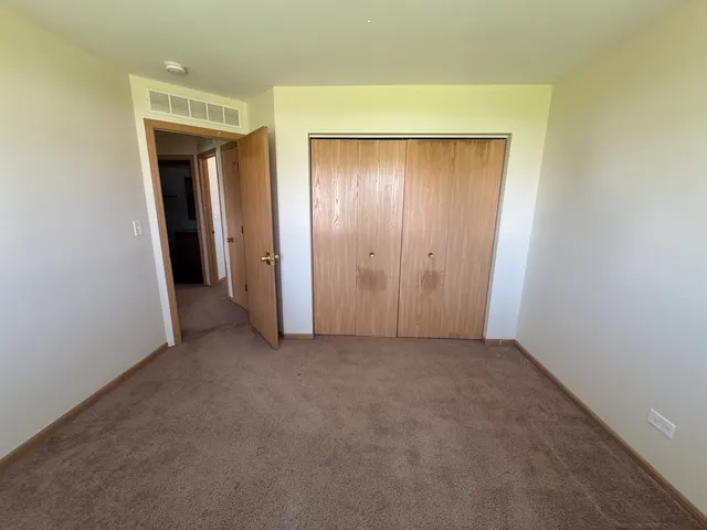 a view of an empty room with closet and a mirror