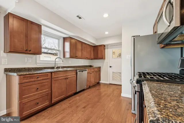 a kitchen with granite countertop wooden cabinets and a stove top oven