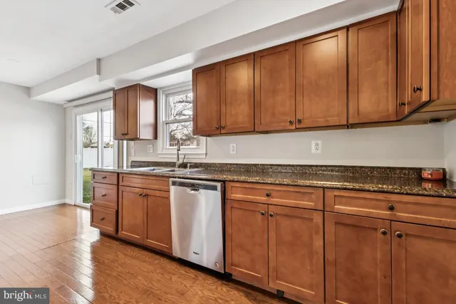 a kitchen with granite countertop wooden cabinets a sink and dishwasher