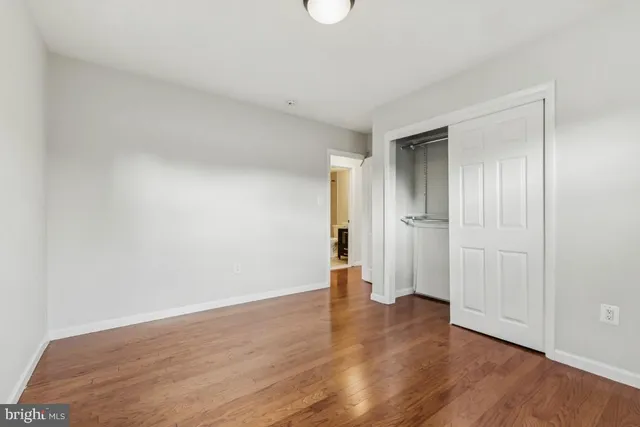 a view of an empty room with wooden floor and closet