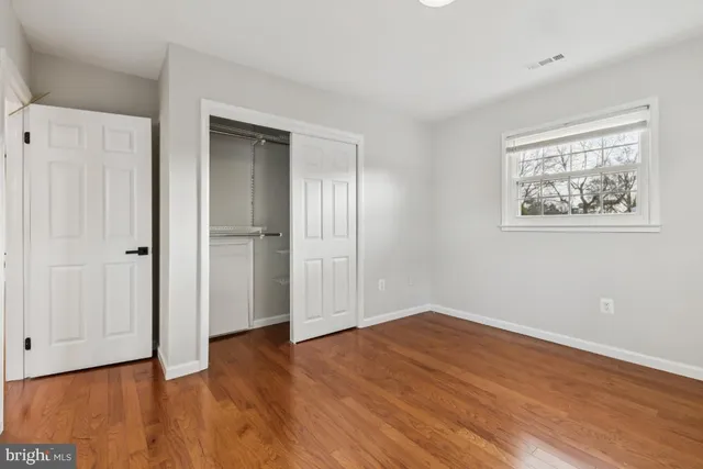 a view of an empty room with wooden floor and closet