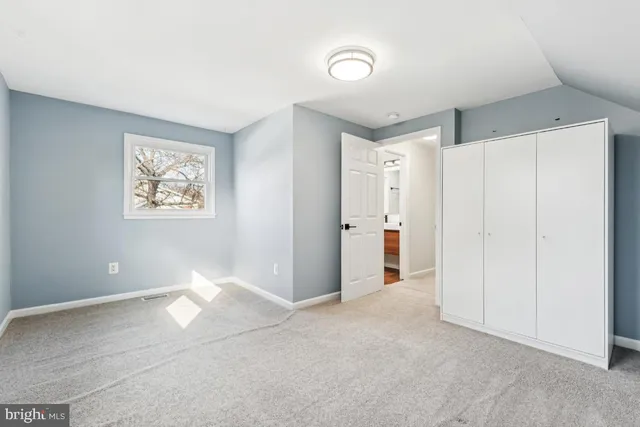 a view of an empty room with closet and a window