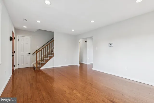 a view of an empty room with wooden floor and stairs