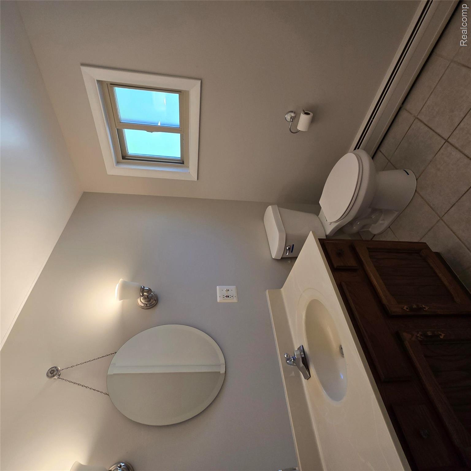 311 Nevada Avenue Rochester, MI 48309 - Photo 44 of 70 Bathroom featuring a wood vanity with integrated sink, a wall-mounted mirror, and sconce lighting