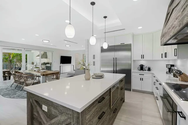 a kitchen with a white center island a sink stainless steel appliances and cabinets