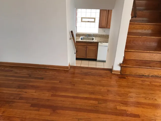 a view of kitchen and empty room with wooden floor
