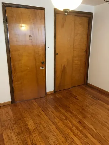 an empty room with wooden floor and entrance