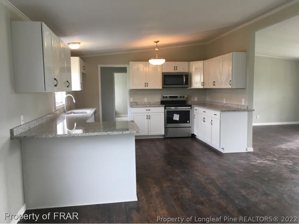 7692 Smithfield Road Godwin, NC 28344 - Photo 6 of 36 a kitchen with stainless steel appliances a sink a stove a microwave a refrigerator a sink and cabinets