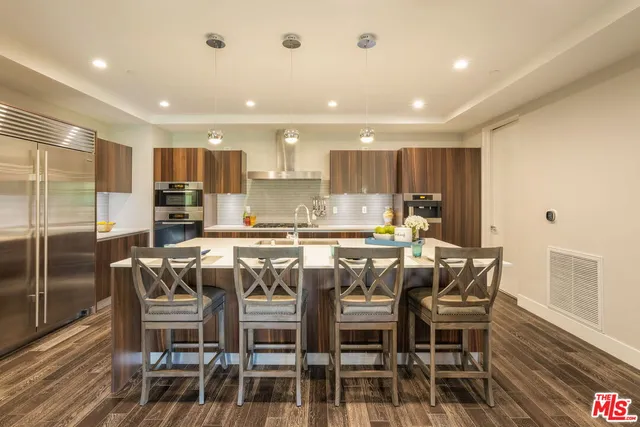 a kitchen with stainless steel appliances granite countertop a dining table chairs and wooden floor