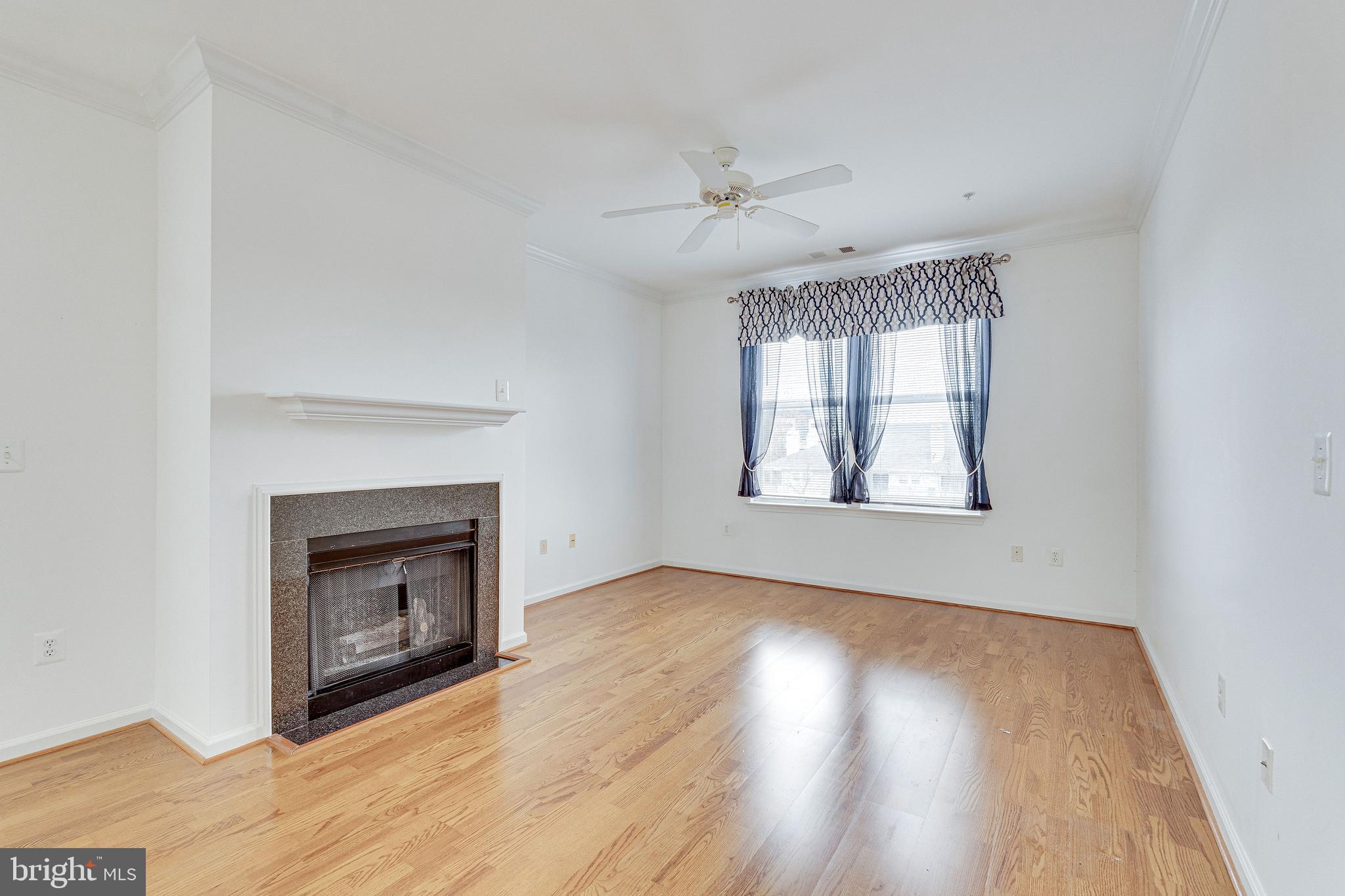 12000 Market Street, Unit 370 Reston, VA 20190 - Photo 9 of 51 an empty room with wooden floor fireplace and windows