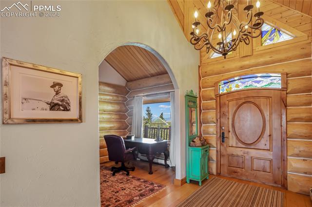 616 Summit Road Hartsel, CO 80449 - Photo 33 of 50 Foyer featuring hardwood / wood-style flooring, a notable chandelier, log walls, and high vaulted ceiling
