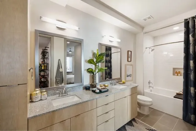 a bathroom with a double vanity sink toilet and a mirror