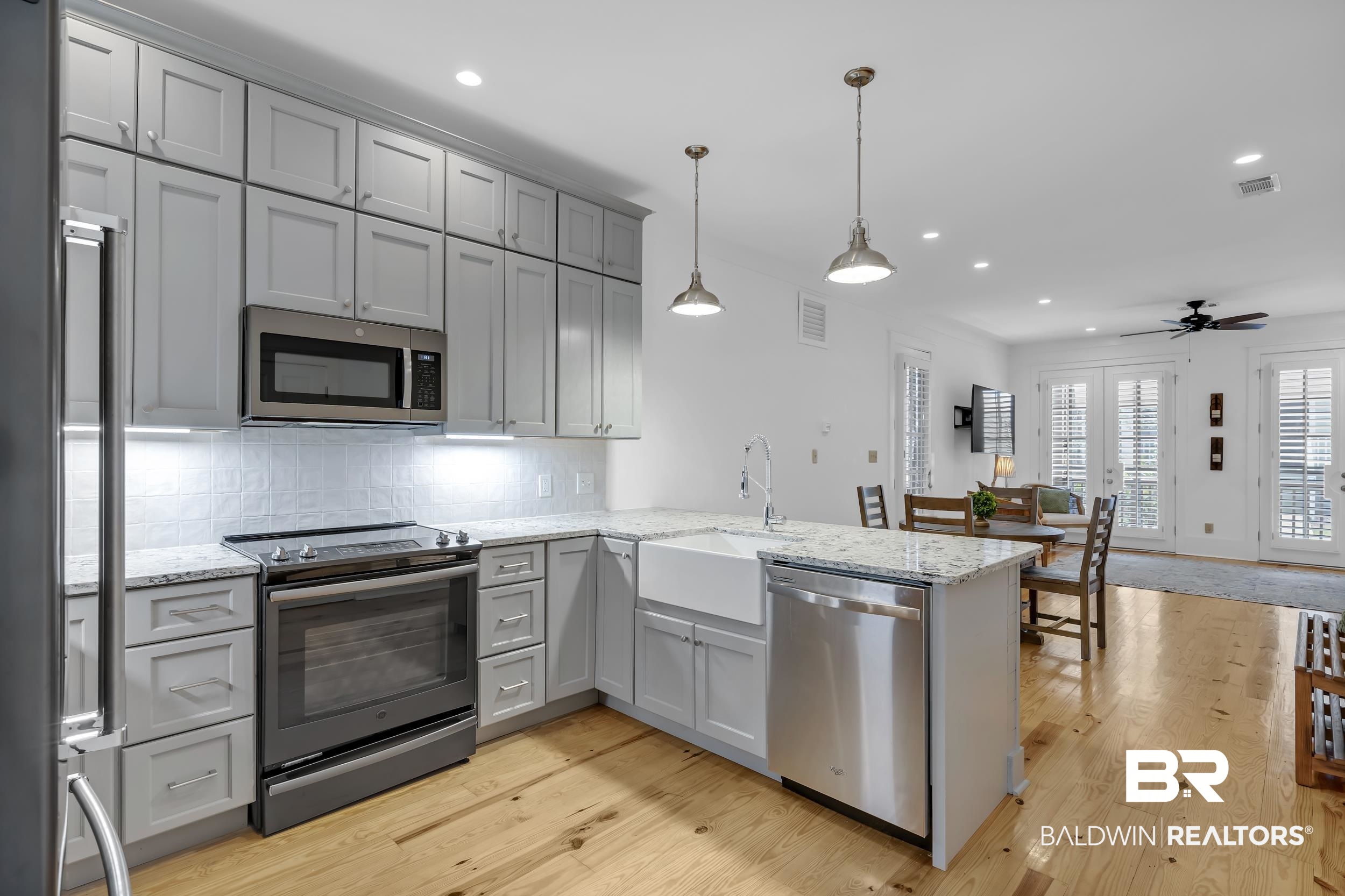 25773 Canal Road, Unit 32 Orange Beach, AL 36561 - Photo 4 of 35 Kitchen featuring stainless steel appliances, light stone countertops, decorative light fixtures, backsplash, and light wood-type flooring