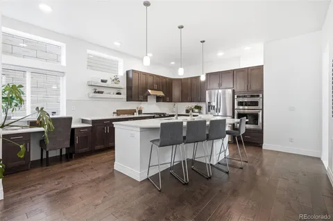 a kitchen with stainless steel appliances kitchen island granite countertop a table chairs and a refrigerator