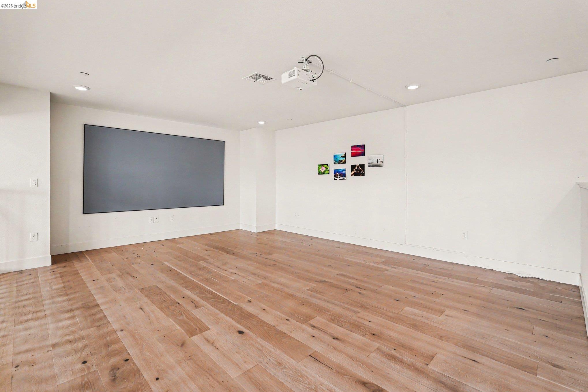 18210 Argento Loop San Ramon, CA 94583 - Photo 27 of 43 Spacious room featuring a large projection screen, mounted projector, recessed lighting, and wide plank wood-finish flooring