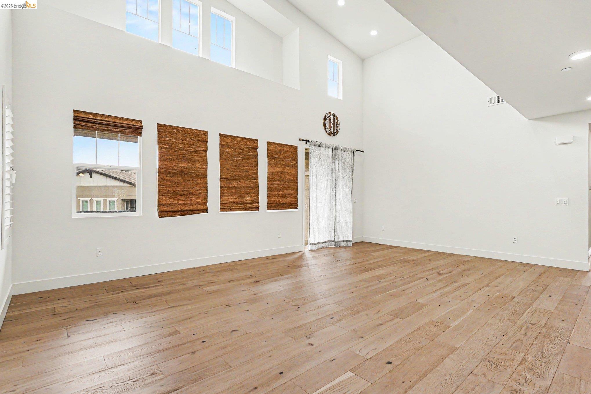 18210 Argento Loop San Ramon, CA 94583 - Photo 7 of 43 Spacious room featuring high vaulted ceilings, light wood-finish flooring, and multiple windows with upper transoms providing natural illumination