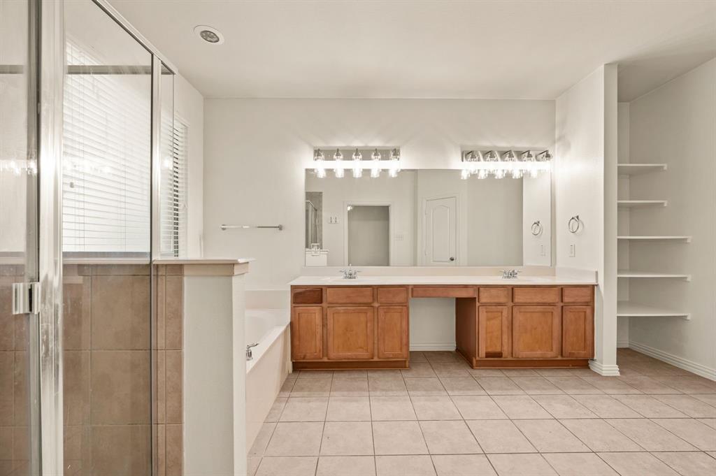808 Briar Ridge Drive Keller, TX 76248 - Photo 18 of 40 Spacious bathroom featuring a dual vanity with wood cabinetry, a large soaking tub, a separate glass-enclosed shower with tile surround, and built-in shelving