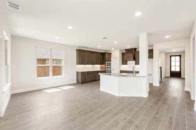 a view of a kitchen with kitchen island wooden floors stainless steel appliances and windows