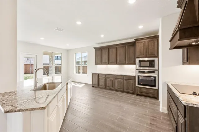 a large kitchen with a large counter top stainless steel appliances and cabinets