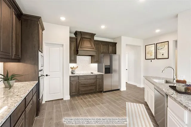 a large kitchen with a stove a sink dishwasher a refrigerator and cabinets with wooden floor