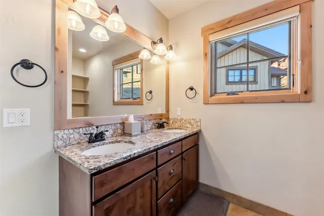 a bathroom with a granite countertop double vanity and a mirror