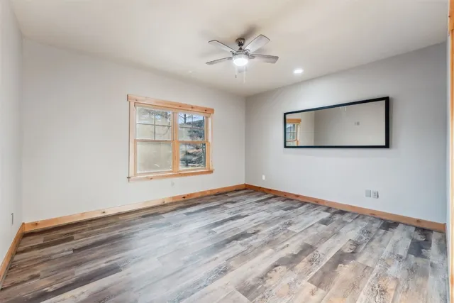 a view of an empty room with window and wooden floor