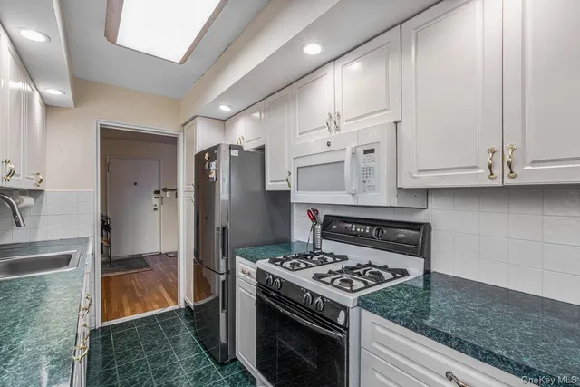 a kitchen with white cabinets and appliances