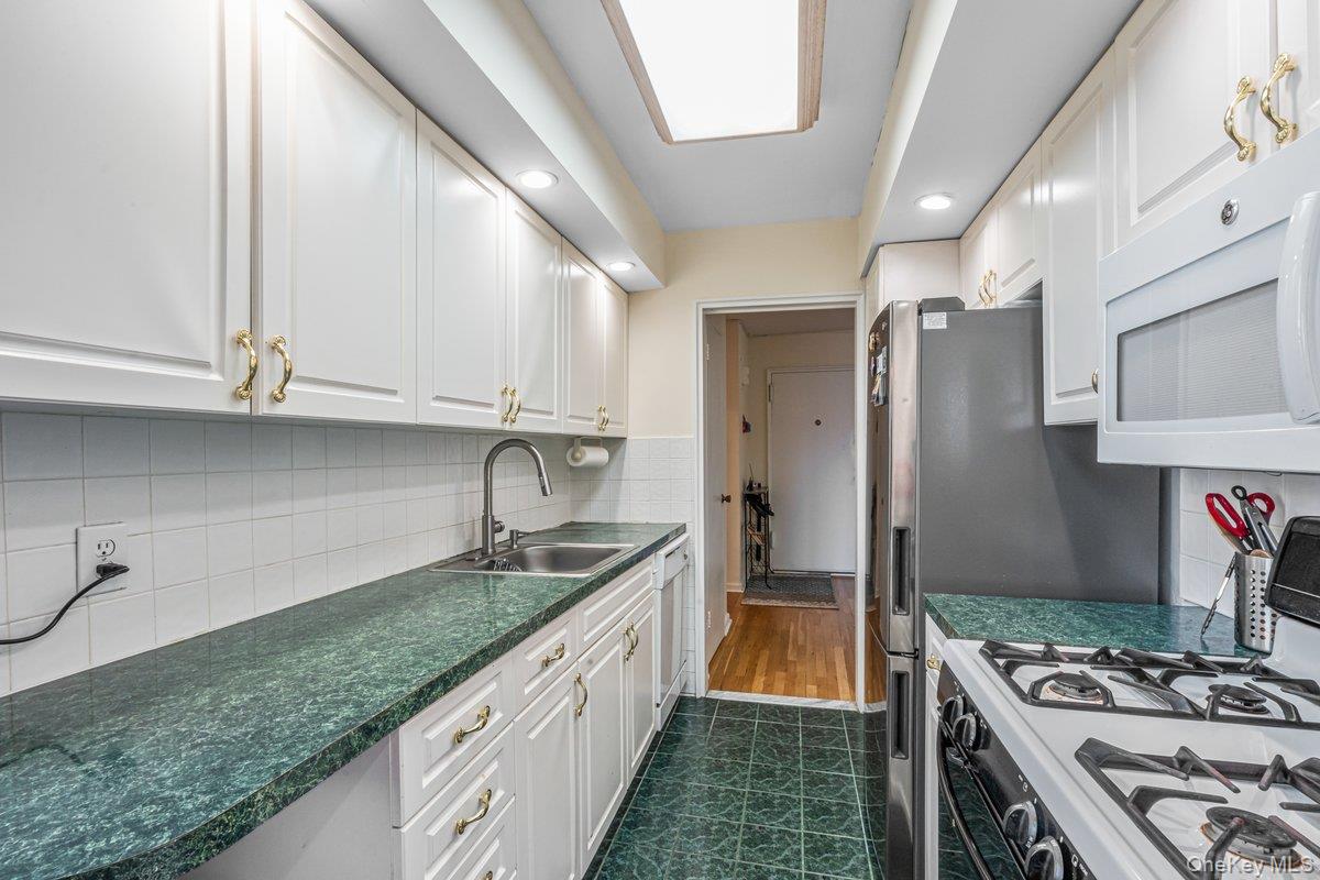 18-50 211th Street, Unit 6B Queens, NY 11360 - Photo 7 of 15 a kitchen with stainless steel appliances granite countertop a sink stove and refrigerator