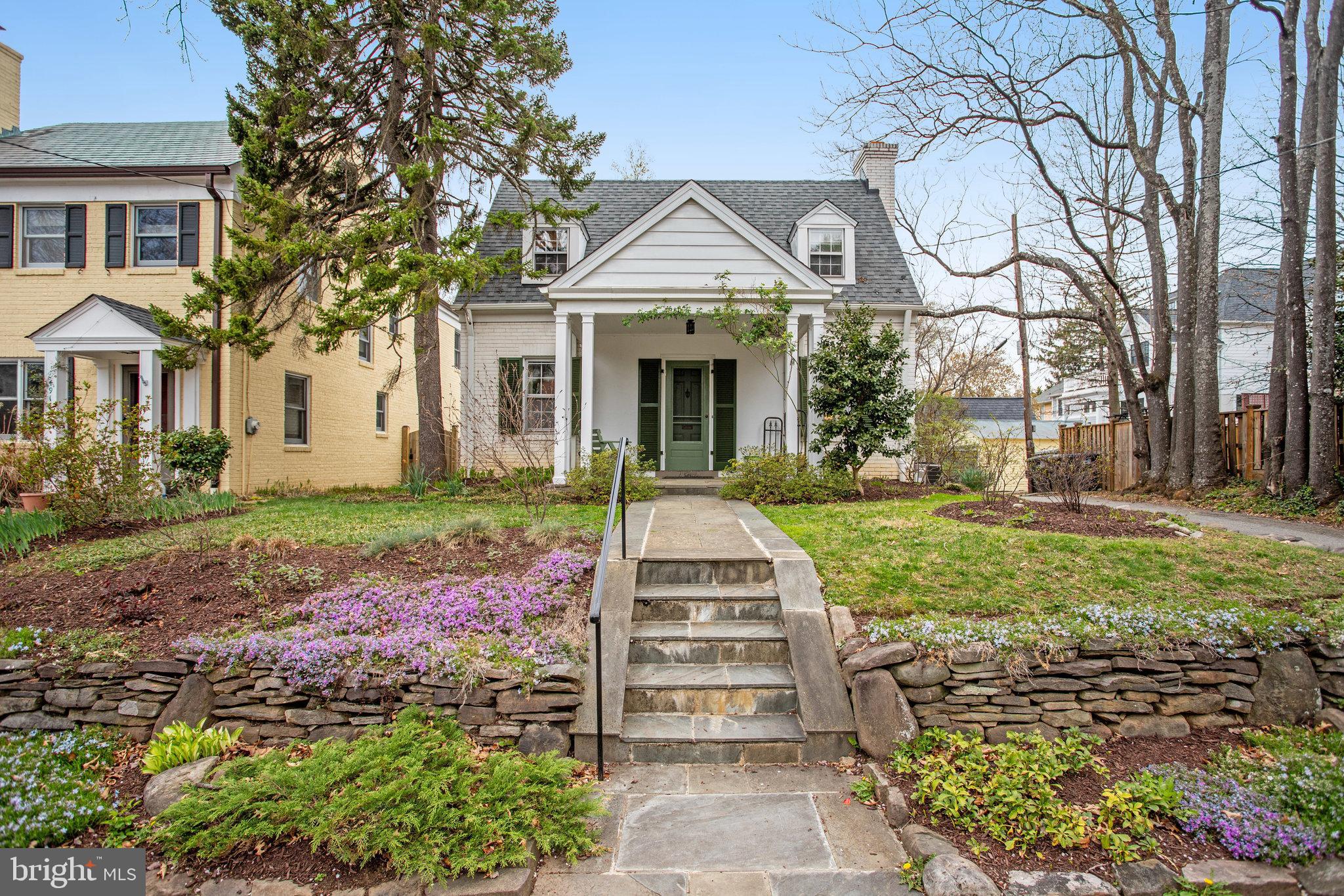 a front view of a house with a garden and trees