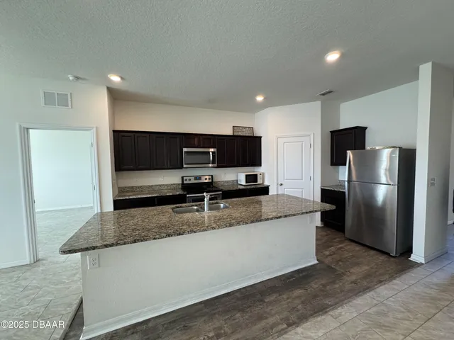 a kitchen with stainless steel appliances granite countertop a refrigerator a stove and a sink