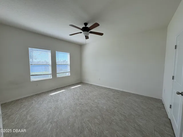 an empty room with windows and fan