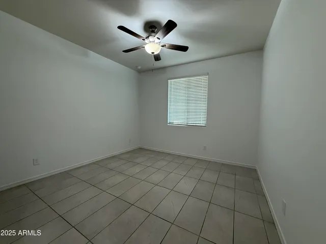 an empty room with windows and ceiling fan