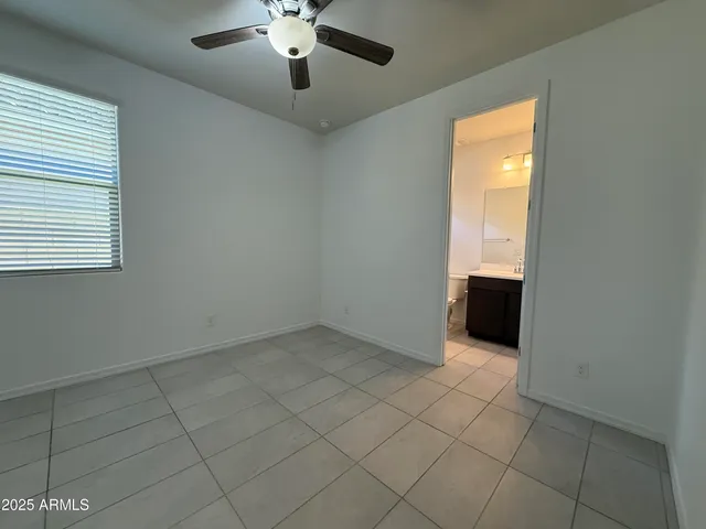 an empty room with chandelier fan and windows