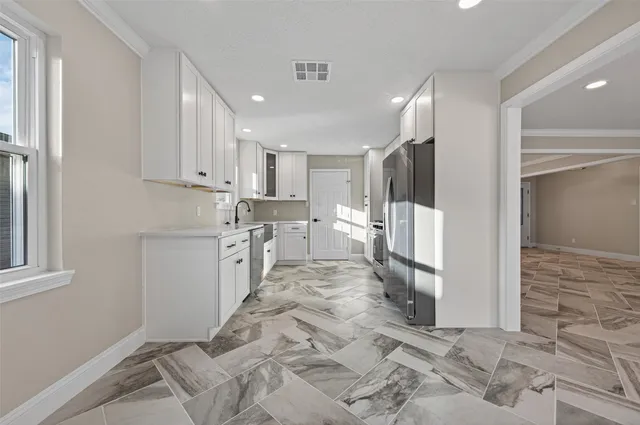 a large white kitchen with white cabinets and stainless steel appliances