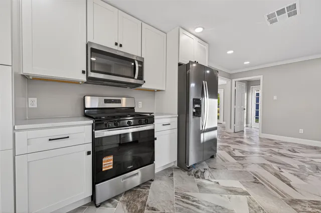 a kitchen with stainless steel appliances granite countertop a stove a refrigerator and a microwave