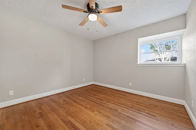 an empty room with wooden floor and ceiling fan