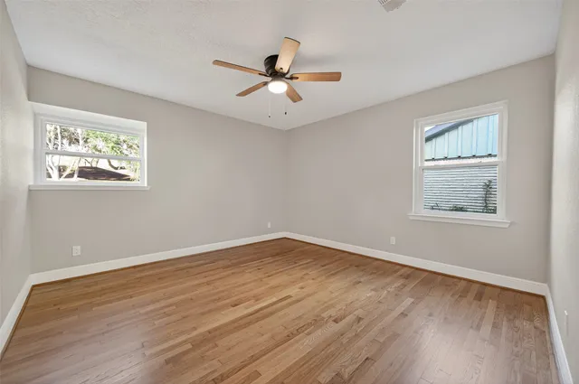 a view of a big room with wooden floor and windows