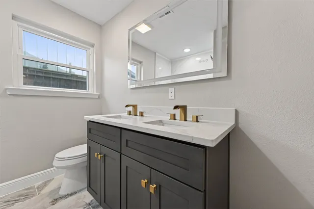 a bathroom with a toilet a sink a mirror and a window