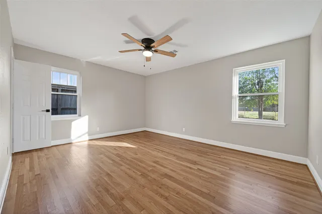 a view of empty room with wooden floor and fan