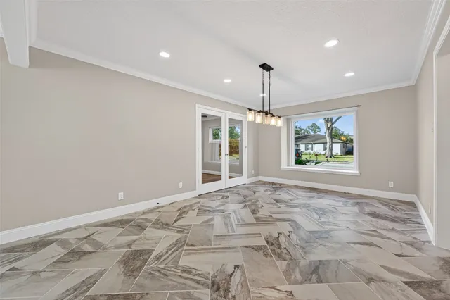a view of an empty room with window and chandelier