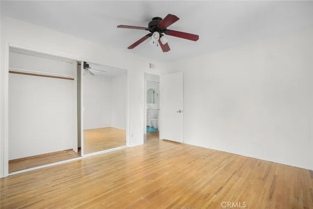 a view of empty room with wooden floor and ceiling fan