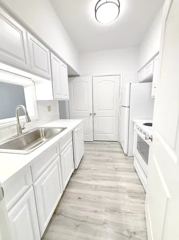 a large white kitchen with sink and white cabinets