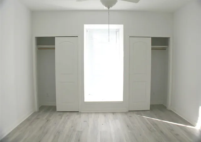 a view of an empty room with closet and a window