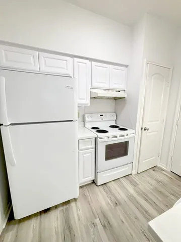 a kitchen with a refrigerator a stove top oven a sink and cabinets