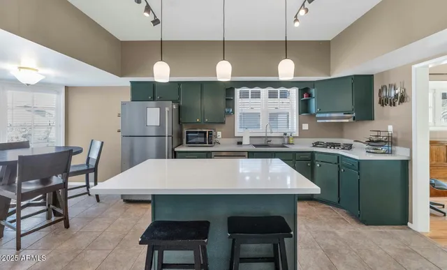 a kitchen with kitchen island a sink a stove a refrigerator and white cabinets
