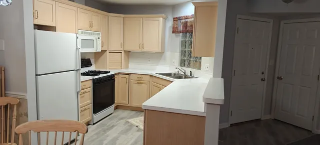 a kitchen with stainless steel appliances a refrigerator a sink and white cabinets
